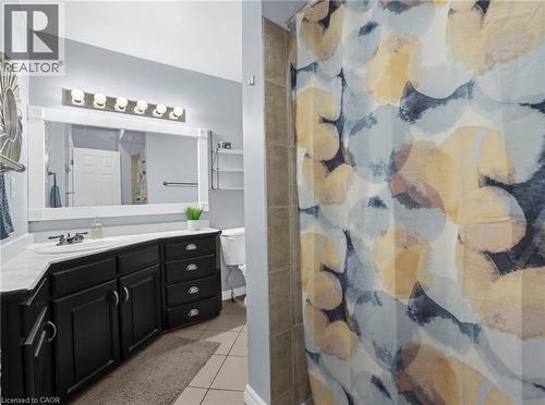 Bathroom featuring a dark wood-finish vanity with an integrated sink, a white countertop, and a vanity mirror with sconce lighting - 420 Waverly Street, Hamilton, ON 