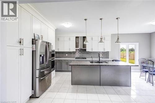 Bright kitchen featuring a central island, white shaker cabinetry, stainless steel appliances, and a gray subway tile backsplash - 417 Rivertrail Avenue, Kitchener, ON 