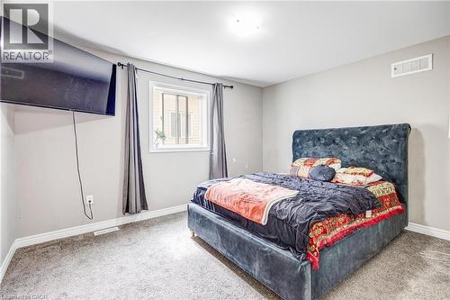 Neutral-toned wall paint with white trim, a single window with dark draperies, and a neutral carpeted floor - 417 Rivertrail Avenue, Kitchener, ON 