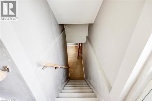 Stairwell with light grey walls, white trim, and a natural wood handrail - 417 Rivertrail Avenue, Kitchener, ON 