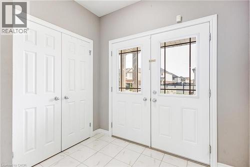 Entryway with white panel doors, dual front entry doors with integrated window panes, and light-toned tile flooring - 417 Rivertrail Avenue, Kitchener, ON 