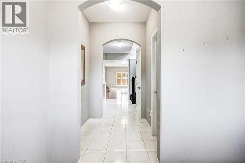 Hallway featuring arched entryways, white tile flooring, and light gray wall paint - 417 Rivertrail Avenue, Kitchener, ON 