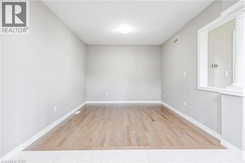 Bright interior room featuring wood-finish flooring, light grey painted walls, white baseboards, and a ceiling-mounted light fixture - 417 Rivertrail Avenue, Kitchener, ON 