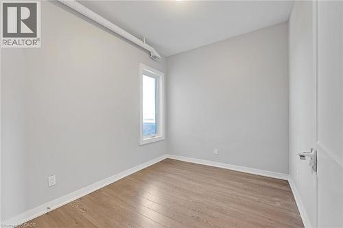 Room featuring wood-finish flooring, light grey walls, and a white-framed window - 657 Barton Street E Unit# 302, Hamilton, ON 