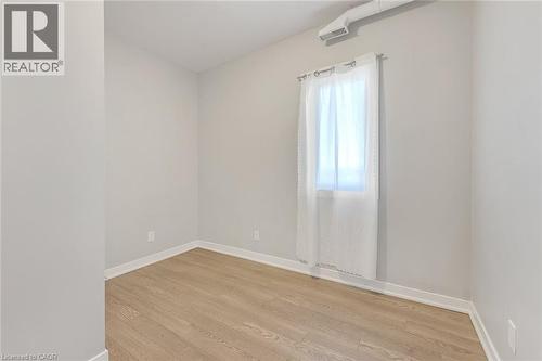 Light-filled interior featuring wood-finish flooring, white baseboards, and a window with a sheer curtain - 657 Barton Street E Unit# 302, Hamilton, ON 