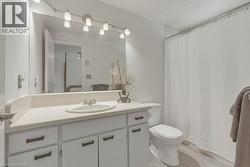 Bathroom featuring a white vanity with an integrated sink, track lighting, and wood-finish flooring - 
