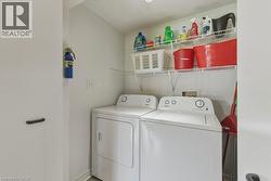 Dedicated laundry area featuring a white washing machine and dryer, overhead wire shelving, and light gray flooring - 