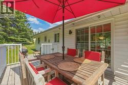 Expansive wood deck with white railings, featuring a sliding glass door entry to the interior - 