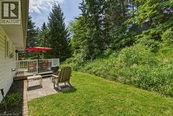 Expansive backyard featuring a manicured lawn, an elevated wood deck with white railings, and a ground-level paver patio - 