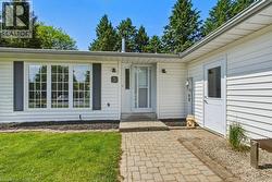 White siding exterior with dark shutters, a front entry door with sidelight, and a paved walkway - 