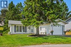 White vinyl siding exterior with an attached garage, featuring a gabled roof and dark decorative shutters - 