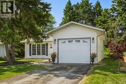 White siding exterior with an attached single-car garage featuring a decorative window panel - 