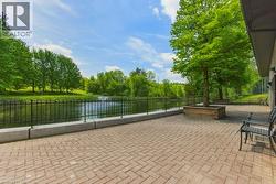 Expansive paver patio overlooking a body of water with a decorative fence - 