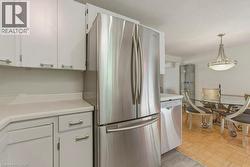 Kitchen featuring white cabinetry, light-toned countertops, and stainless steel appliances including a built-in refrigerator and dishwasher - 