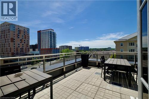 Spacious outdoor patio featuring paver flooring, glass and metal railing, and urban skyline backdrop - 246 Lester Street Unit# 306, Waterloo, ON 