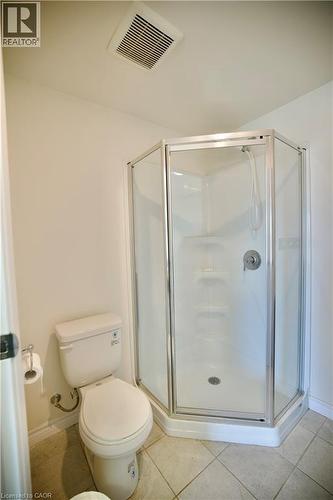 Corner shower with glass enclosure and white base, porcelain toilet, and light-toned floor tiling - 246 Lester Street Unit# 306, Waterloo, ON 