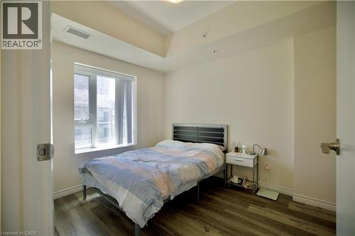 Bedroom featuring wood-finish flooring, a window providing natural light, and neutral wall tones - 246 Lester Street Unit# 306, Waterloo, ON 