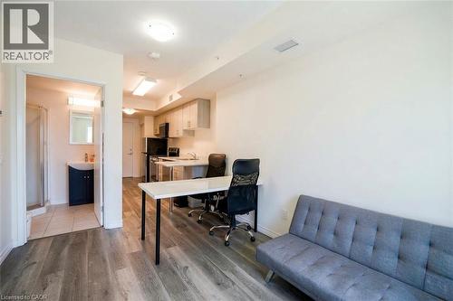 Open-concept living space featuring wood-finish flooring, a kitchen area with light cabinetry and appliances, and an adjacent bathroom with a shower enclosure and vanity - 246 Lester Street Unit# 306, Waterloo, ON 