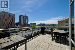 Spacious outdoor patio featuring paver flooring, glass and metal railing, and urban skyline backdrop - 