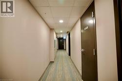 Hallway featuring light beige walls, a drop ceiling with recessed lighting, and patterned carpet flooring - 