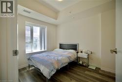 Bedroom featuring wood-finish flooring, a window providing natural light, and neutral wall tones - 