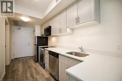 Kitchen featuring wood-finish flooring, light wood-grain cabinetry, light-toned countertops, and stainless steel appliances - 