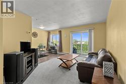 Living area featuring a sliding glass door to the balcony, wood-finish flooring, two large windows, and an overhead light fixture - 