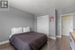 Bedroom featuring wood-finish flooring, neutral gray walls, and white baseboards - 