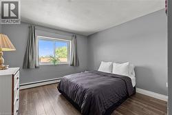 Bedroom featuring wood-finish flooring, a double window, and light grey wall finishes - 