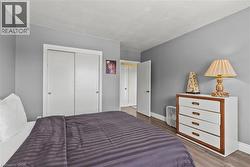 Bedroom featuring wood-finish flooring, light gray wall paint, white baseboards, and a white sliding closet door - 