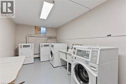 Dedicated laundry area featuring multiple white washers and dryers, a utility sink, and a table - 