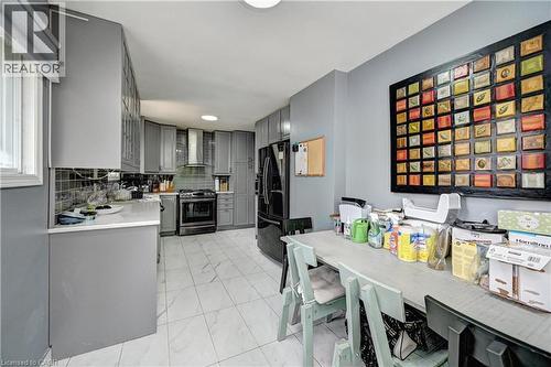 Modern kitchen featuring grey cabinetry, white countertops, tile flooring, stainless steel range, and a coordinating range hood - 525 Fallingbrook Drive, Waterloo, ON 