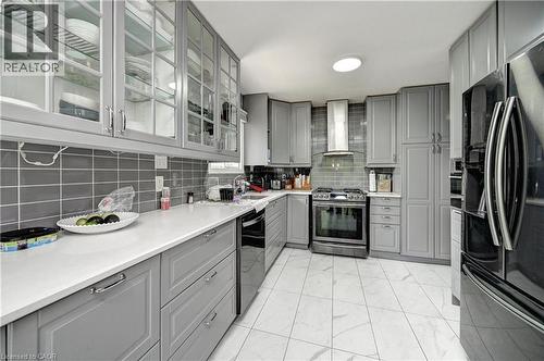 Contemporary kitchen featuring gray cabinetry with glass-front upper cabinets, white countertops, and a subway tile backsplash - 525 Fallingbrook Drive, Waterloo, ON 