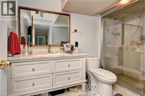 Bathroom featuring a light-toned vanity with an integrated sink, a framed mirror, a toilet, and a glass-enclosed shower with a rainfall showerhead - 525 Fallingbrook Drive, Waterloo, ON 