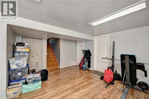 Finished lower level featuring wood-finish flooring, light grey walls, white trim, and a white paneled door - 525 Fallingbrook Drive, Waterloo, ON 