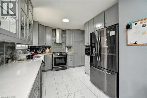 Contemporary kitchen featuring gray cabinetry, white countertops, stainless steel appliances, a tiled backsplash, and light-toned floor tiling - 525 Fallingbrook Drive, Waterloo, ON 