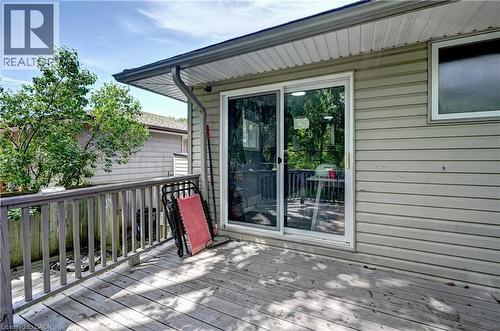 Outdoor wood deck with a wooden railing, featuring a large sliding glass door and a horizontal window - 525 Fallingbrook Drive, Waterloo, ON 