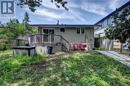 Rear exterior featuring a wooden deck with railing, sliding glass doors, and two windows - 525 Fallingbrook Drive, Waterloo, ON 