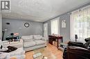 Living space featuring wood-finish flooring, two large windows, a white entry door, recessed lighting, and a textured ceiling - 525 Fallingbrook Drive, Waterloo, ON 