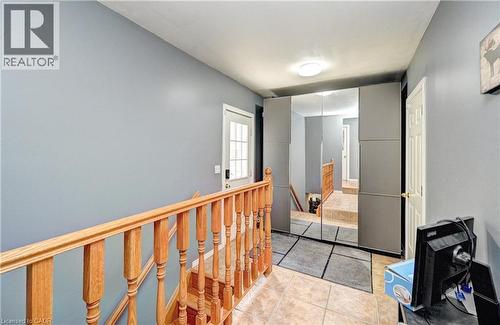 Upper floor landing with wood railing, light blue walls, and ceramic tile flooring - 525 Fallingbrook Drive, Waterloo, ON 
