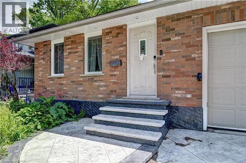 Brick exterior featuring a white entry door with decorative glass, white-framed windows, and a panel garage door - 525 Fallingbrook Drive, Waterloo, ON 