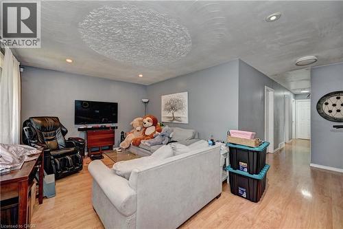 Living area featuring light wood-finish flooring, recessed lighting, a neutral gray wall color, a white ceiling, and a hallway with white doors - 525 Fallingbrook Drive, Waterloo, ON 