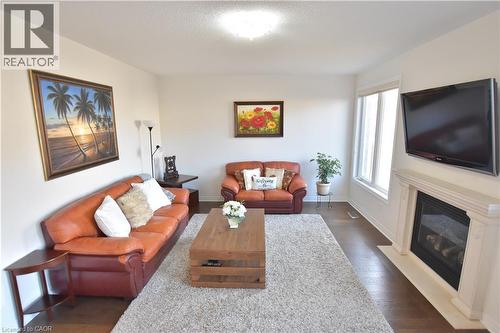 Living room featuring dark wood finished floors and a fireplace with flush hearth - 512 Terrington Crescent, Kitchener, ON 