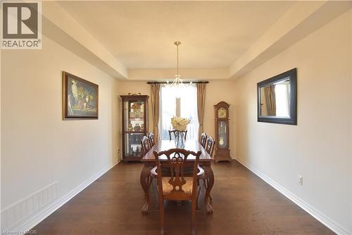 Dining space featuring dark wood-style floors, a tray ceiling, and a chandelier - 512 Terrington Crescent, Kitchener, ON 