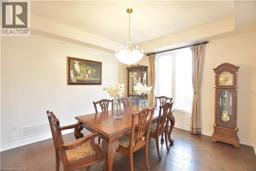 Dining area featuring dark wood-style flooring, a chandelier, and a tray ceiling - 512 Terrington Crescent, Kitchener, ON 