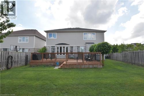 Expansive backyard featuring a large wooden deck with dark railings, a manicured lawn, and perimeter fencing - 512 Terrington Crescent, Kitchener, ON 