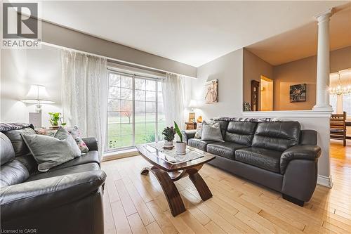 Bright living area featuring light wood-finish flooring and a large window overlooking a landscaped green space - 70 Webster Road, Hamilton, ON 