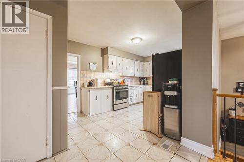 Kitchen featuring white cabinetry, tile flooring, stainless steel range, and a tiled backsplash - 70 Webster Road, Hamilton, ON 