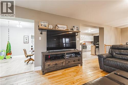 Hardwood-style flooring extends throughout the main living area, featuring a built-in shelving unit with an integrated television mount - 70 Webster Road, Hamilton, ON 