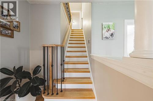 Staircase featuring wood-finish treads, white risers, a wood-finish handrail, and black metal balusters - 70 Webster Road, Hamilton, ON 